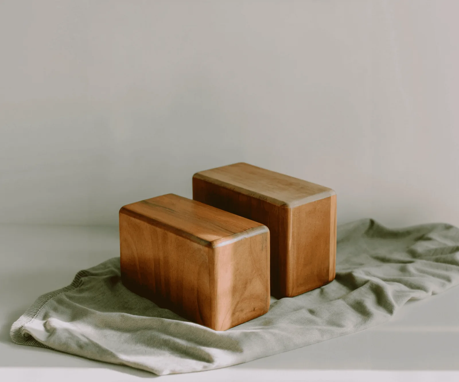 Two wooden yoga blocks on a sage green cloth
